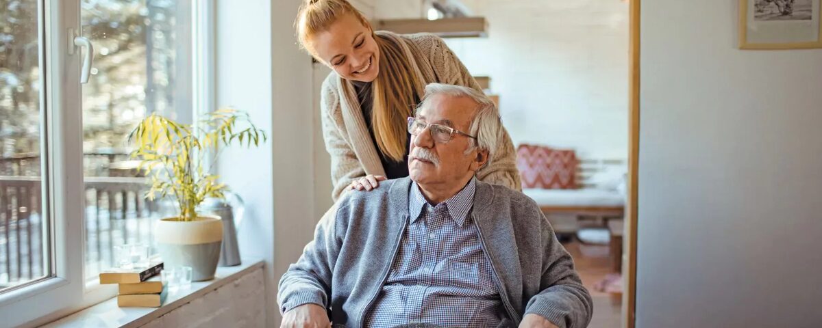 man met snor in rolstoel met vrouw er achter