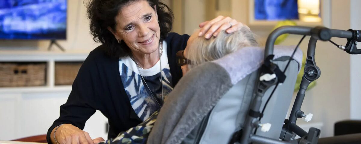 medewerker aait over hoofd client in rolstoel