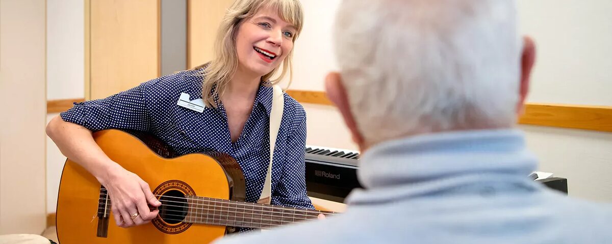 vrouw met gitaar in hand speelt voor client