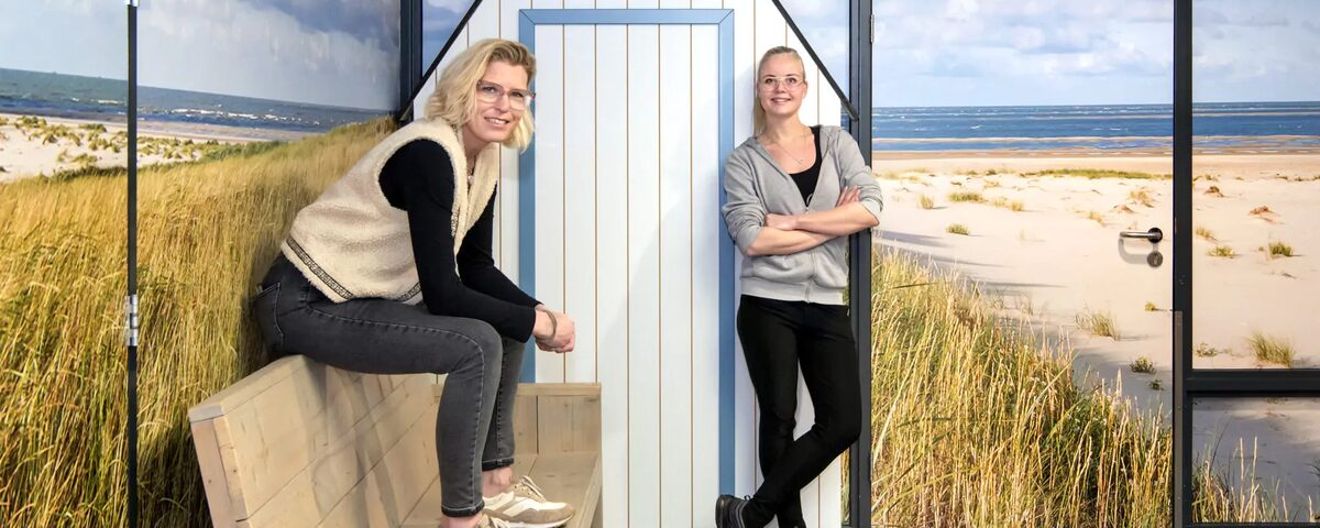 vrouw zit op bank met vrouw die leunt tegen de muur