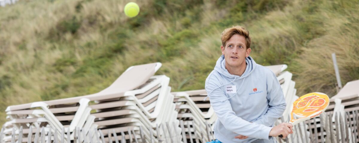 jongen buiten op het strand speelt beach tennis