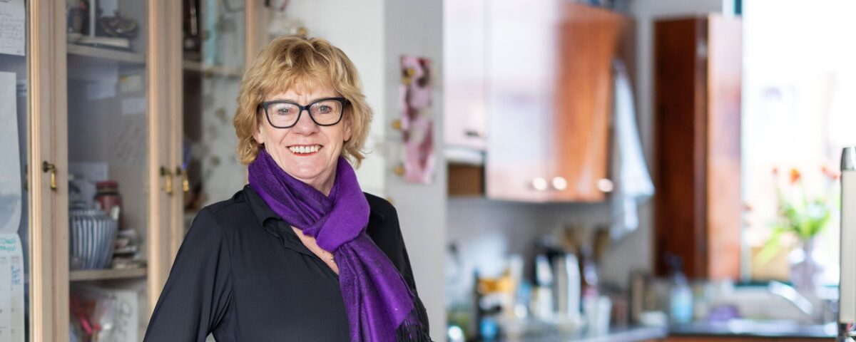 huishoudelijke hulp staat in keuken met paarse kleding
