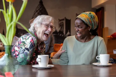 blije client naast vrouw aan tafel met koffie kopjes
