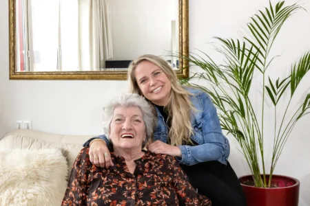 client in rolstoel met daar achter vrouw
