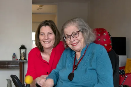 client in rolstoel met helpende plus daarnaast