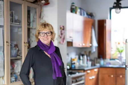 huishoudelijke hulp staat in keuken met paarse kleding