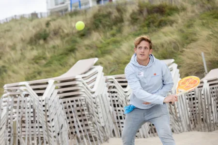 jongen buiten op het strand speelt beach tennis
