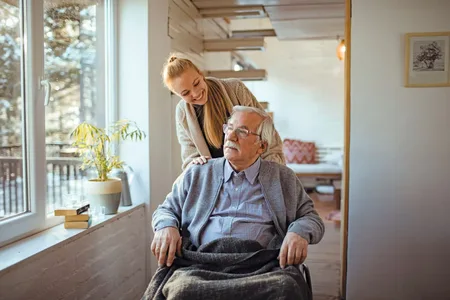 man met snor in rolstoel met vrouw er achter
