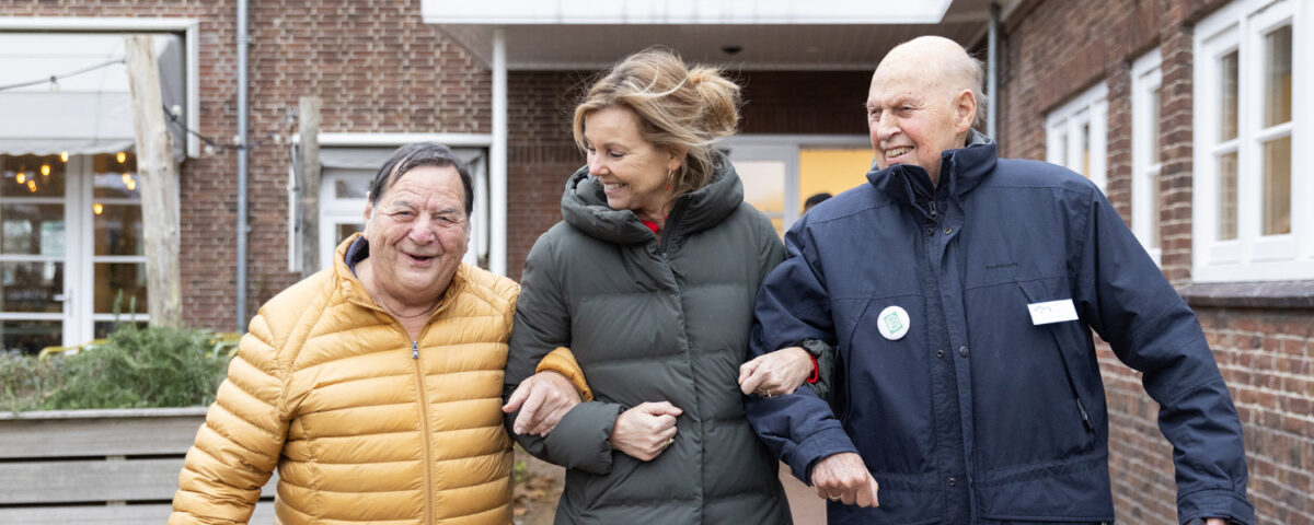 vrijwilliger met twee heren lachend.