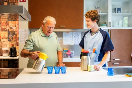 zorgmedewerker naast man in keuken met kannen