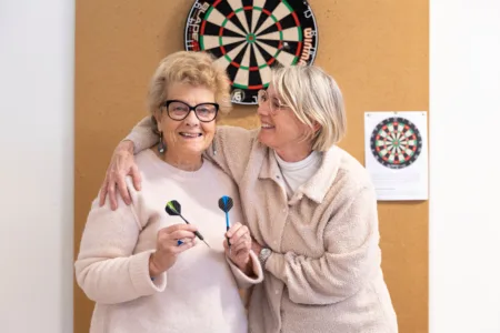 Vrijwilliger samen met cliënt voor het dartbord.