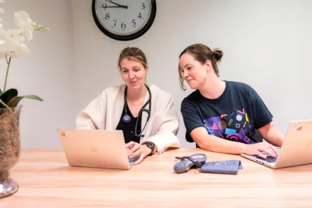Twee medewerkers werken samen op laptop